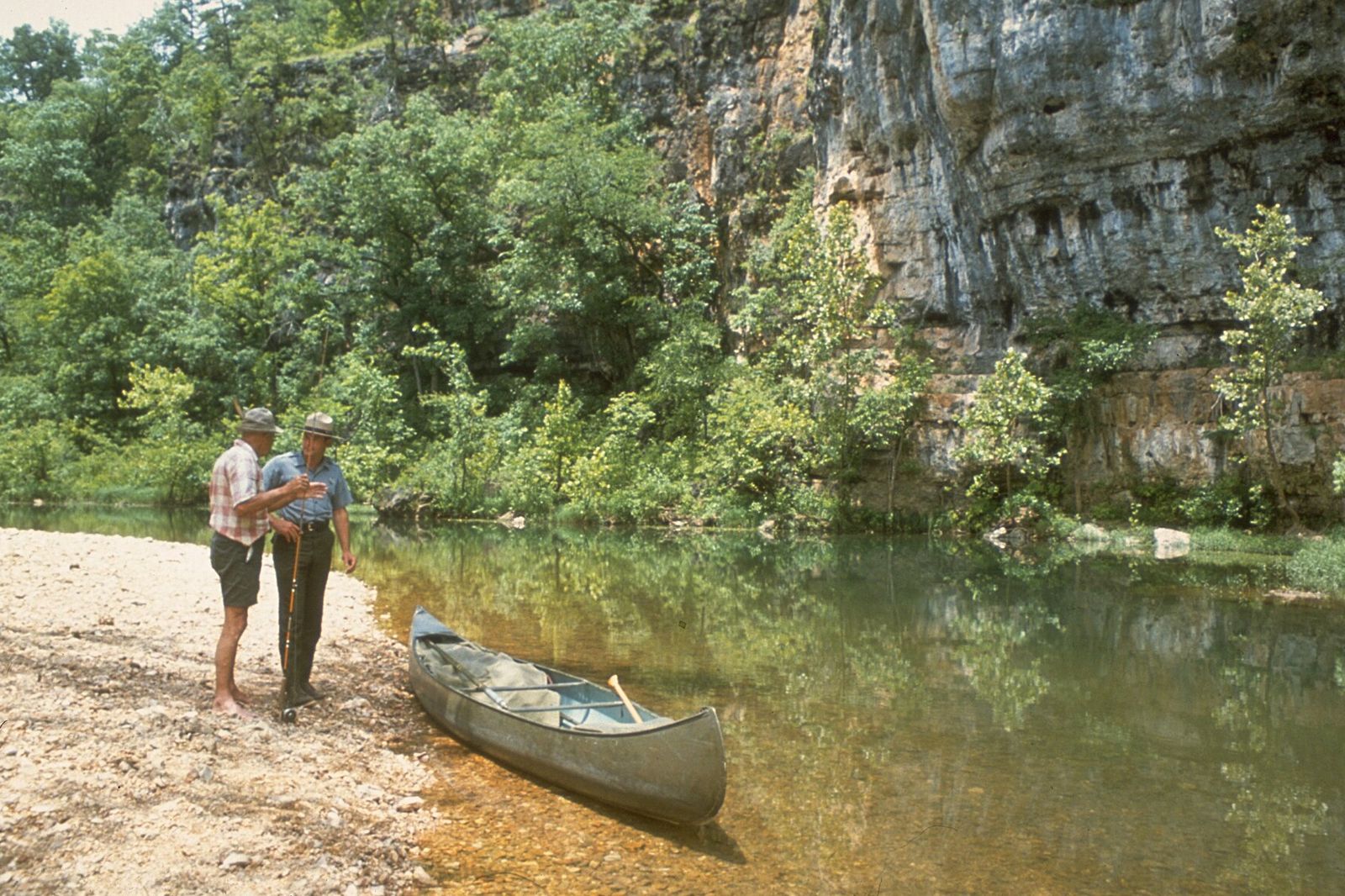 Limestone bluff above a gravel bar and canoe on a clear Ozark river in southern Missouri